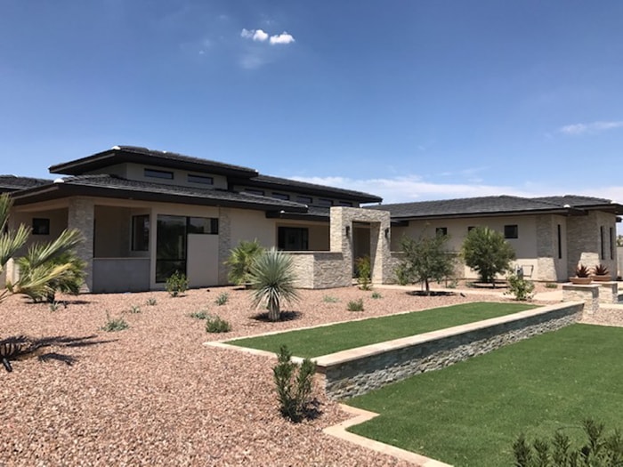 Arizona gray house with large rock and grass front yard